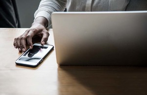 Женщина работает за ноутбуком и трогает телефон