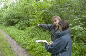 Image of two women pointing at a path in front of trees