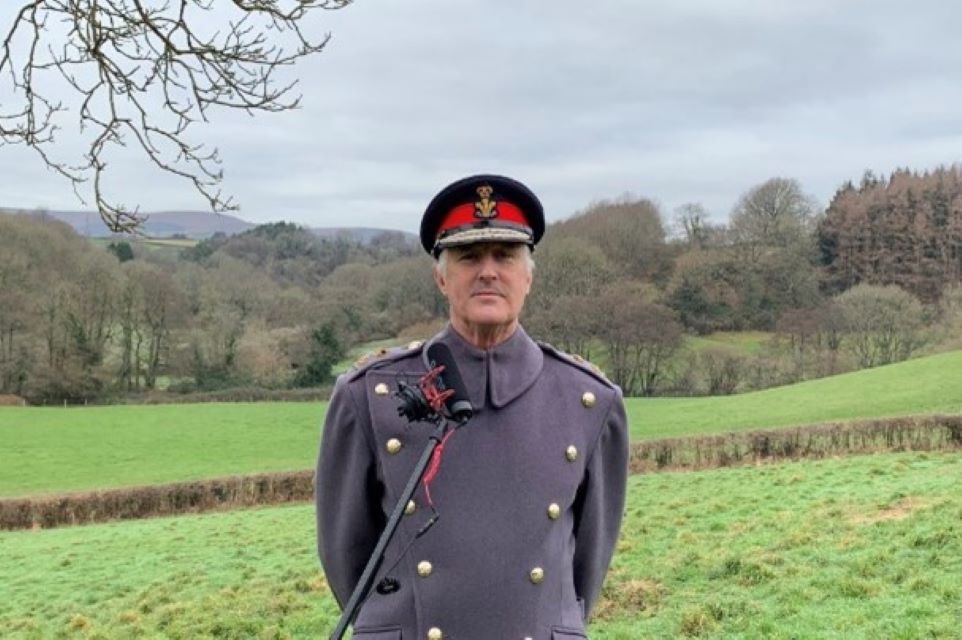 Military man smiling against country backdrop.
