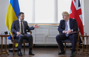 Борис Джонсон и Владимир Зеленский сидят под флагами Великобритании и Украины.