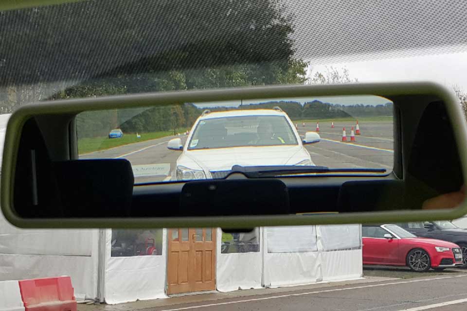 изображение, показывающее внутреннюю часть зеркала заднего вида автомобиля, за которым следует автомобиль