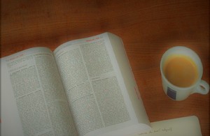 Учебник на столе с чашкой кофе рядом