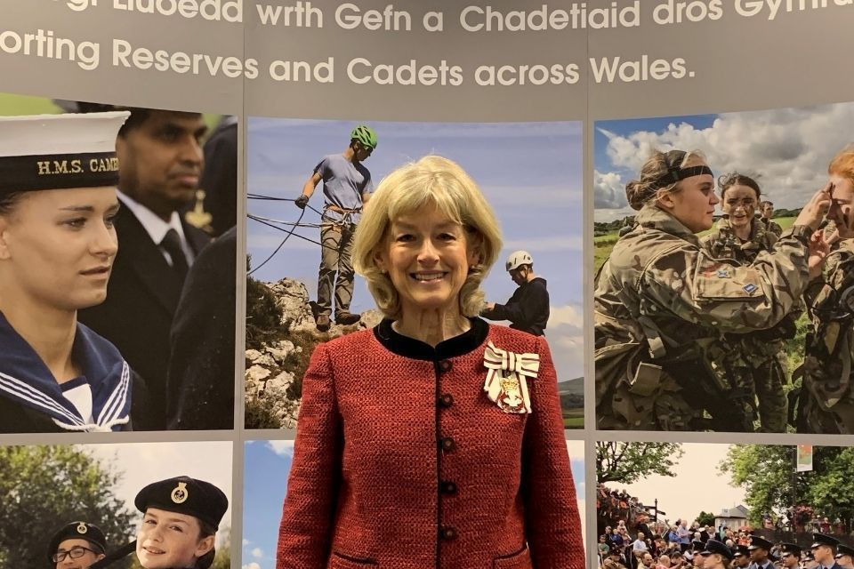 Lady smiling and standing in front of a military backdrop.