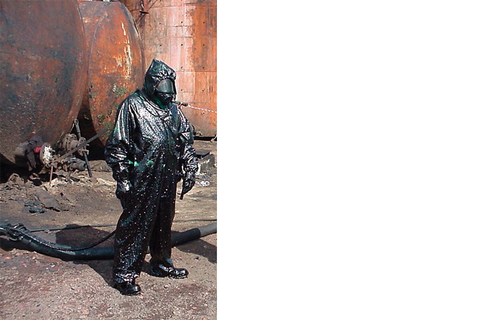 Человек, одетый в защитный костюм, покрытый черной грязью.