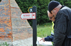 Двое мужчин просматривают документы рядом со знаками права проезда на тренировочной площадке Солсбери-Плейн.