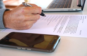 Изображение, показывающее руку человека в офисе с ручкой над контрактными документами