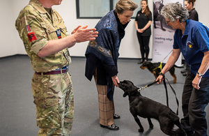 HRH The Princess Royal strokes a dog held by a trainer
