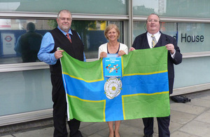 Charles Ashburner (Flag Institute Chief Executive), Helen Edwards (DCLG Director General), and Graham Bartram (Chief Vexillologist, Flag Institute) hold the North Riding flag.