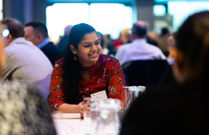 A lady sitting with colleagues smiling while she discusses work