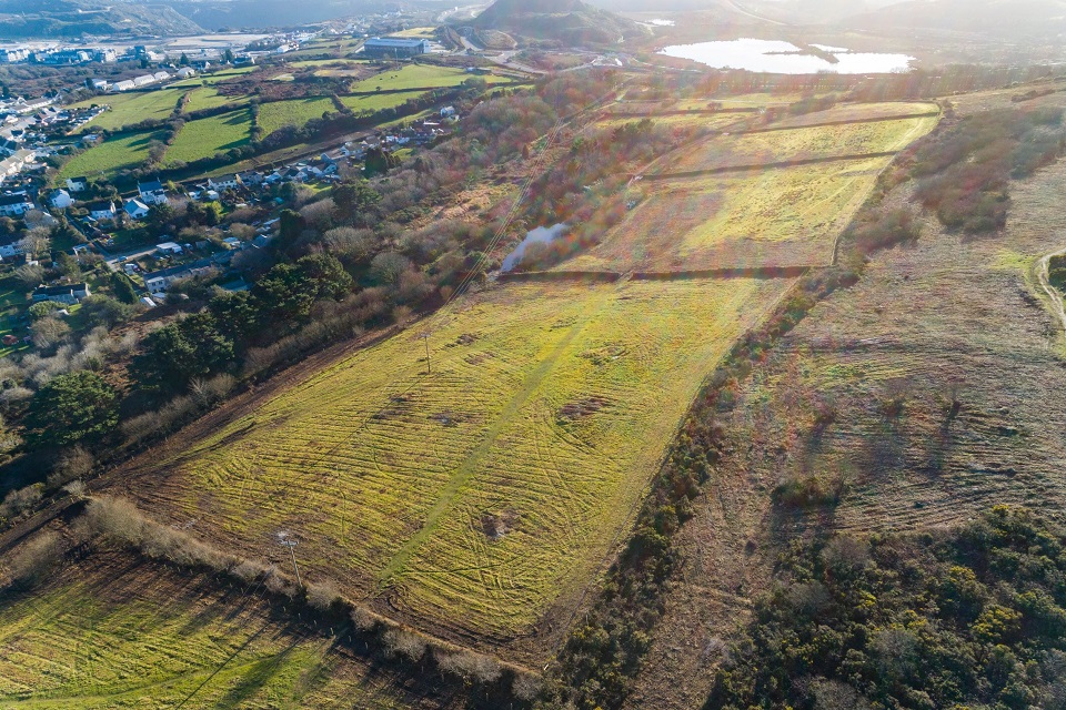 Aerial shot of a large field where land to one side is a different shade and texture where vegetation has been removed