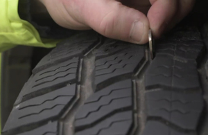 image showing a tyre and a hand placing a 20 pence piece in the thread