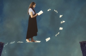 Woman reading while walking in air between cliff edges with sheets of paper floating under her feet.