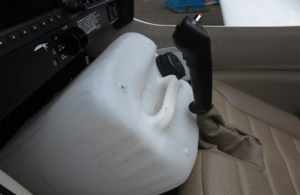 De-icing fluid container positioned at an angle with its base in contact with the rudder pedal adjustment rail