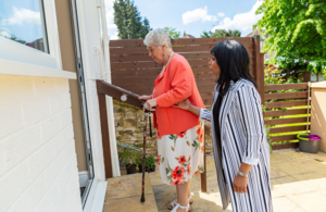 Woman and carer walking up steps to a door