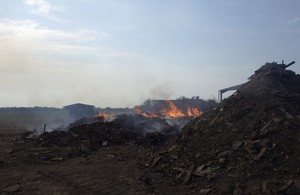 Burning piles of waste, with flames and smoke.