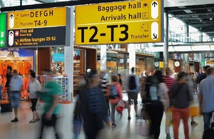 Оживленный торговый зал аэропорта с указателями на багажный зал и зал прибытия.