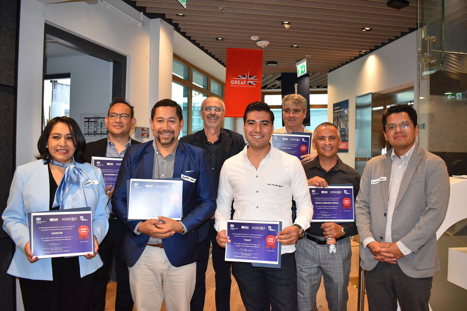 A group of eight people pose and smile for the camera holding certificates in their hands. 