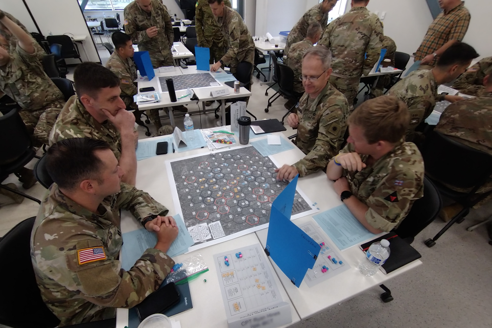 People in uniform sit around a table and play a war game
