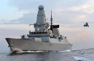 A Sea King Mk7 Airborne Surveillance and Control helicopter approaches HMS Diamond's stern in the Gulf