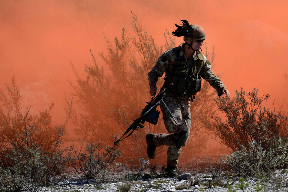 An Italian soldier runs in front of concealing coloured smoke