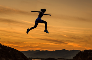 Woman athlete leaping across mountain peaks