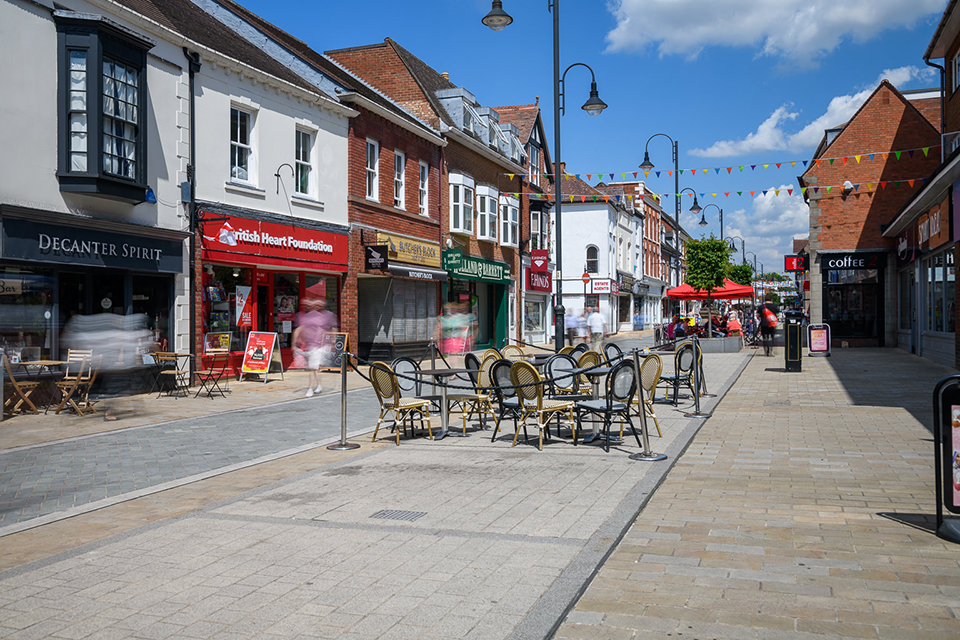 An empty pedestrianised Bromsgrove High Street on a sunny day, with bunting and arranged outside the shops in the middle of the street.