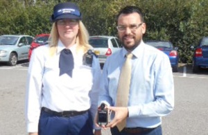 A woman in uniform and a man holding a small camera.