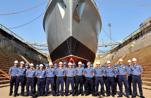 HMS Chiddingfold in dry dock at Portsmouth Naval Base with members of the ship's company