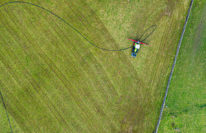 фермер распыляет навозную жижу на зеленом поле, вид сверху