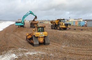 Excavators and lorries are shown moving shingle around Seaford beach to retain protection froim flooding