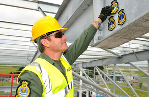 Lt Cdr Chris Trubshaw, Commanding officer 849 Squadron, displays the badges of the three squadrons who will occupy the completed building.