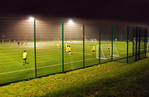 Young people playing on a multi-sport astro turf pitch under floodlights