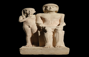 A photo of an Egyptian limestone sculpture from circa 2400 BC to 2300 BC that depicts the priest Mehernefer of the vulture goddess Nekhbet seated next to his standing son