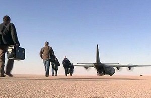 Oilfield workers make their way to an RAF C-130 Hercules transport aircraft at an airfield in the Libyan desert