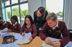 Teacher helping some secondary school pupils.