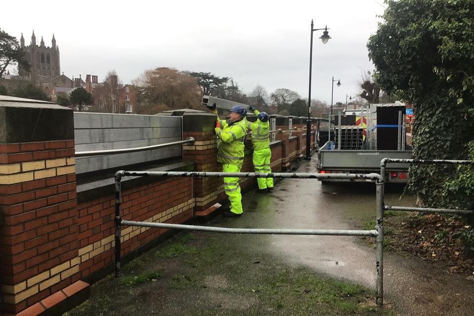 Men in yellow jackets build a flood barrier at Hereford