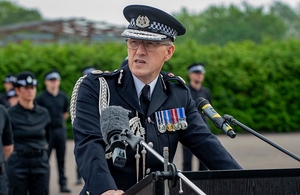 Chief Constable Andy Adams standing at a lectern presenting to the audience of a new recruit pass out parade