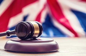 A judge's wooden gavel in front of the Union Jack flag.