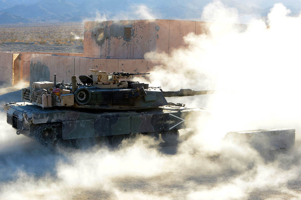 An American M1 Abrams tank fires on an enemy position