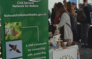 People looking at information on stalls, next to a banner, at the Climate and Environment Conference