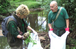 Two volunteers clearing up a river bank