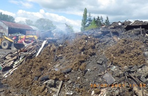 A pile of smouldering rubbish on top of earth and construction waste