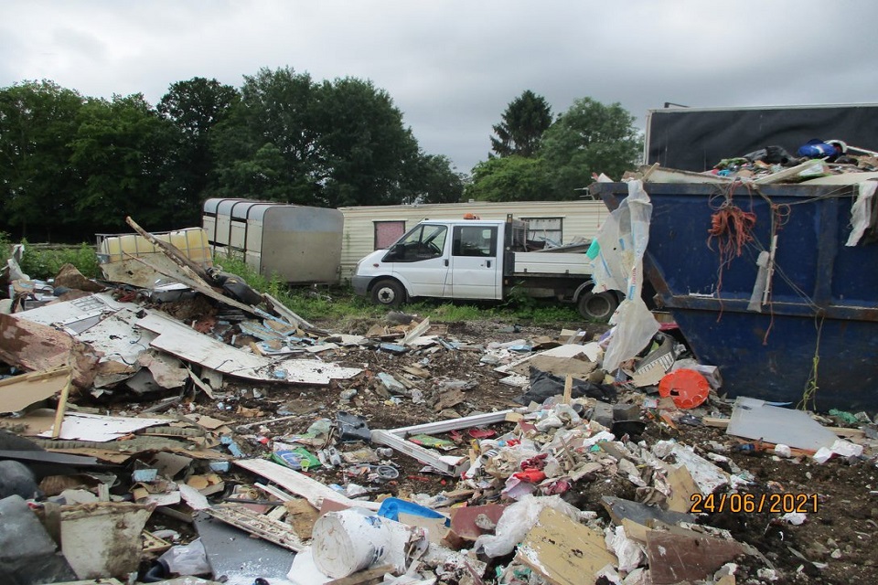 Outbuildings, a white van and construction waste can be seen