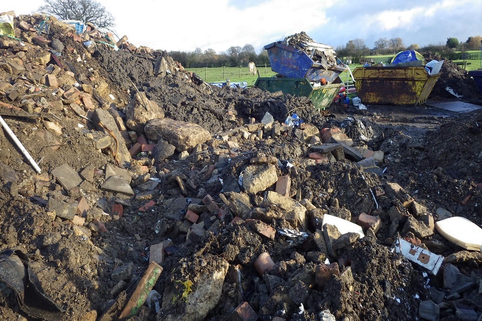 A huge mountain of waste is seen in front of empty skips 