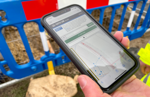 Person holding a mobile phone showing the NUAR platform on screen