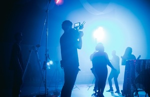 Оператор снимает силуэты людей на съемочной площадке, освещенной синим светом.