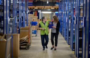Two female colleagues discussing work in a warehouse.