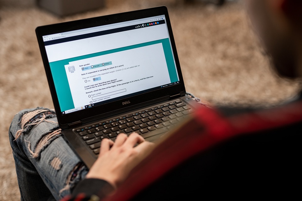 Man filling out a questionnaire on a computer he has on his lap.