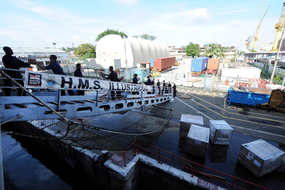 Service personnel load humanitarian supplies onto HMS Illustrious