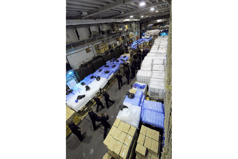 Service personnel load humanitarian supplies onto HMS Illustrious